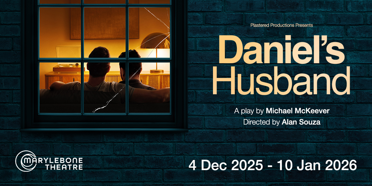 A couple sits together on a sofa, smiling, with warm lighting and neutral-toned decor in the background.