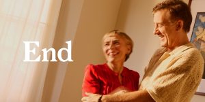 A man and woman smile and embrace, illuminated by soft light, with the word "End" prominently displayed.