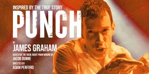 A professional setting with a diverse group of people discussing around a table, with documents and laptops.