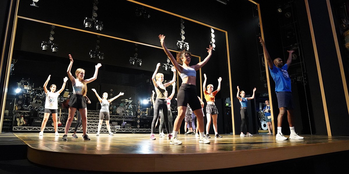 Children learning dance with cast of Tina The Tina Turner Musical