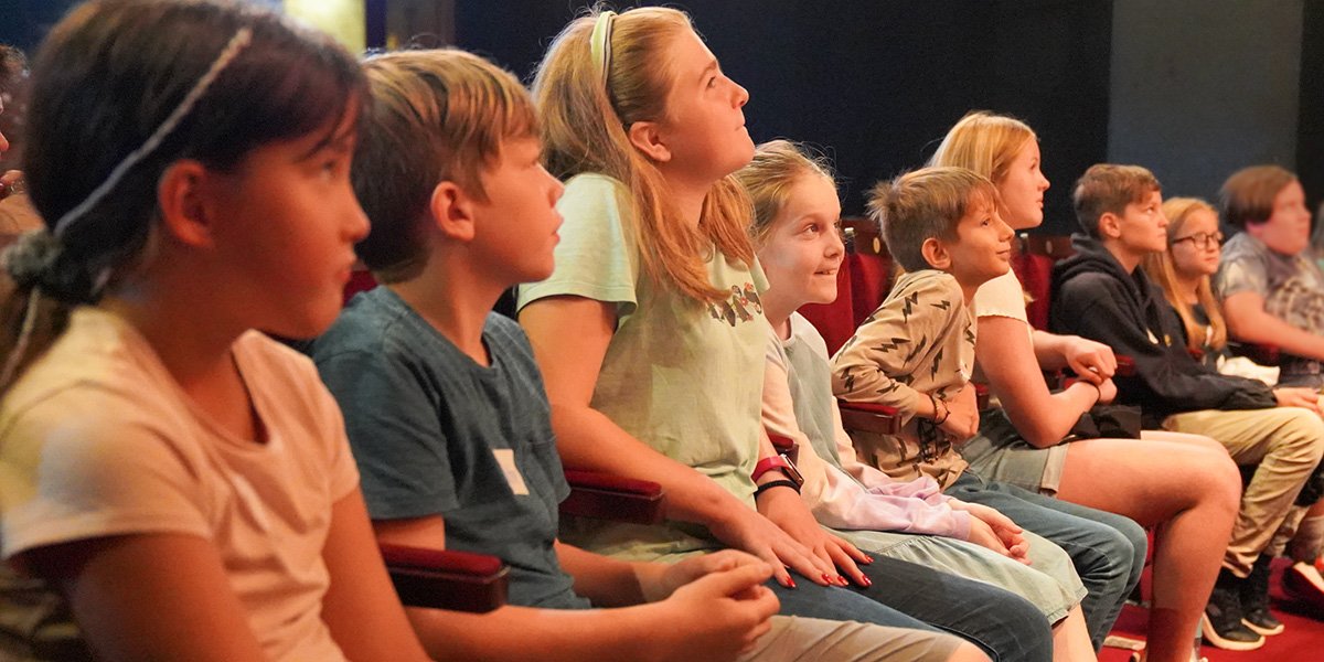 A row of seated children enjoying the theatre