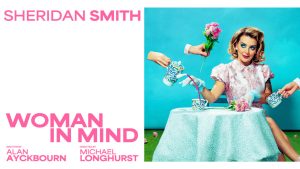 A woman with long brown hair sits thoughtfully, gazing into the distance against a soft, blurred background.