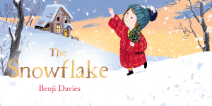 A young girl with brown hair smiles, holding a snowflake decoration against a snowy background.